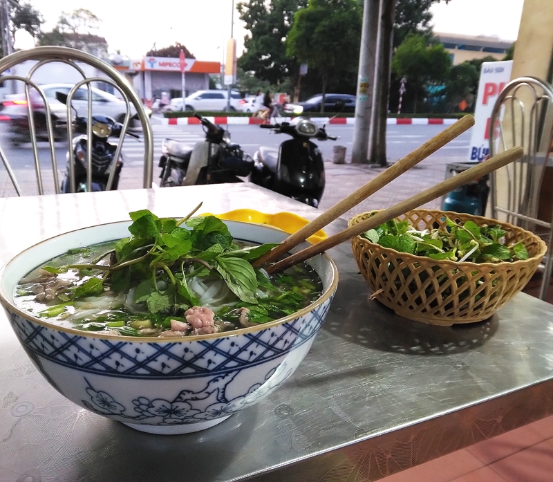 通りを行き交う人やバイクを見ながらフォーをいただく